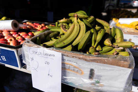A box of green bananas with handwritten sign reads &ldquo;Green banana $2.00/kg&rdquo;