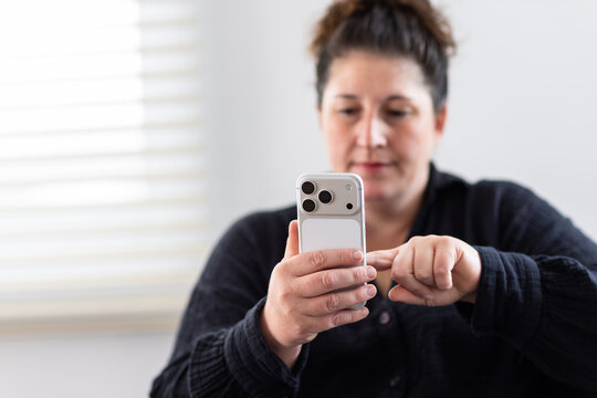 Woman in black shirt holding and tapping a touch screen smart phone