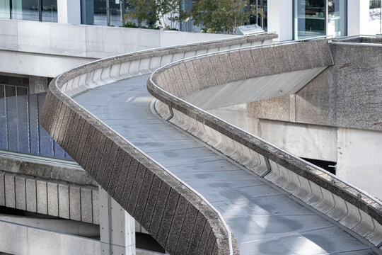 Curved concrete ramp in Paris forming flowing lines through modern architecture with a pedestrian pathway extending along the curved concrete ramp