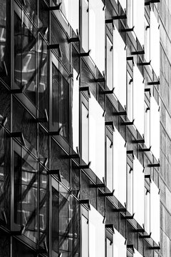 Monochrome building facade in Paris with repeating windows and geometric pattern photographed vertically to emphasize the rhythm of the architecture