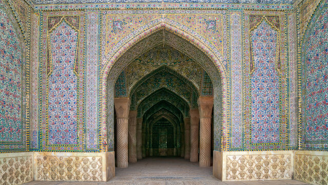 Vakil Mosque in Shiraz, Iran, a Zand dynasty masterpiece, with a symmetrical facade of pink, blue and yellow floral tiles around the arched prayer hall doorway