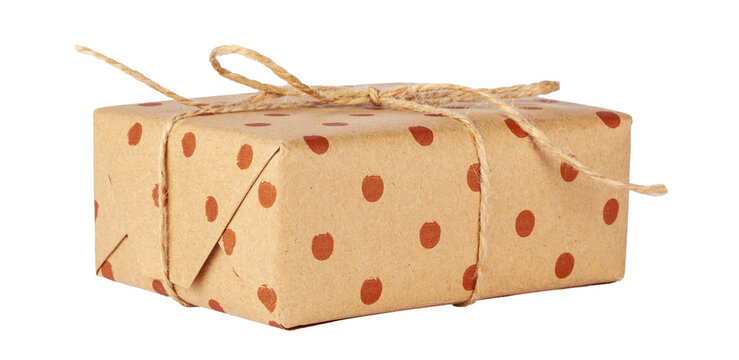 Wrapped gift box with brown polka dots and twine on top sitting on a plain surface