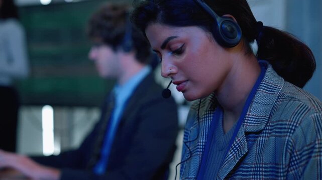 Female technology professional wearing a headset and working at a computer in a modern office, representing technical support, customer service, digital communication, remote assistance, and business 