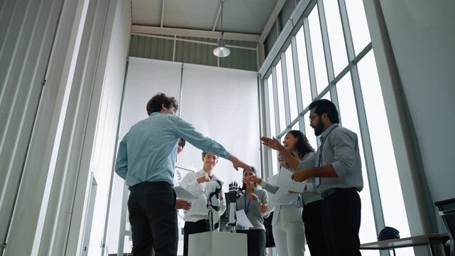 Diverse engineering team celebrating a successful robotics project by raising their hands and throwing papers in a modern laboratory, representing teamwork, achievement, innovation, and technological 