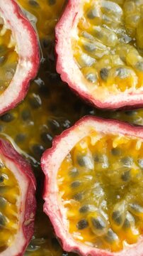 Top view of passion fruit halves rotating slowly over background of juicy pulp