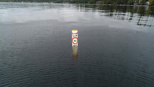 Buoy with warning sign floats on serene lake water