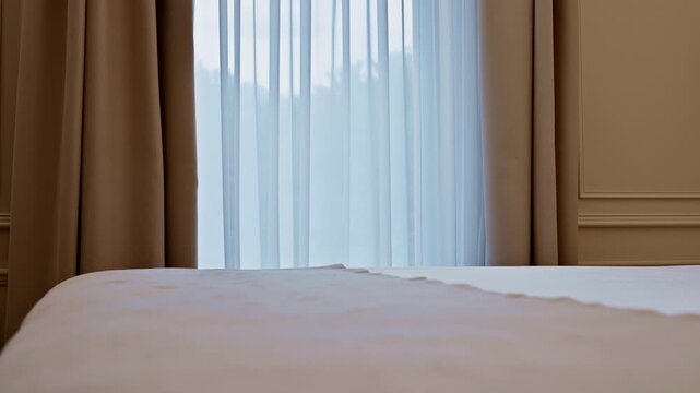 Camera tracks forward in hotel bedroom toward window