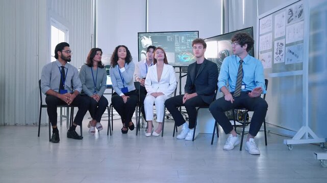 Diverse team of engineers and technology professionals sitting together in a modern robotics laboratory with digital displays and technical diagrams.
