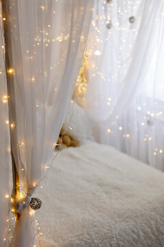 Beautiful christmas decorated bed with drapes and lights, white pure christmas elegant background