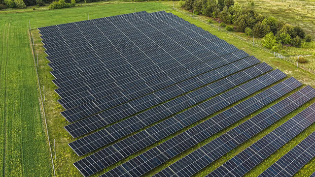 Modern solar farm situated beside vibrant green agricultural crop field