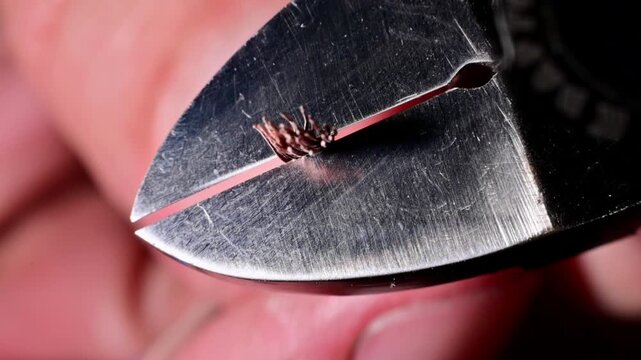Wire cutters slicing through copper wire bundle close up