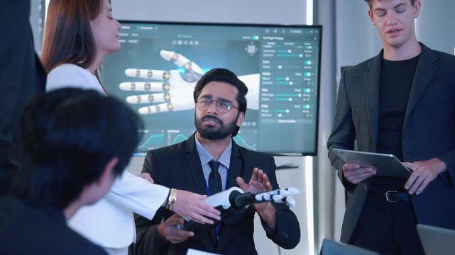 Engineers and technology professionals examining a robotic prosthetic hand prototype during a collaborative meeting in a modern robotics workspace.
