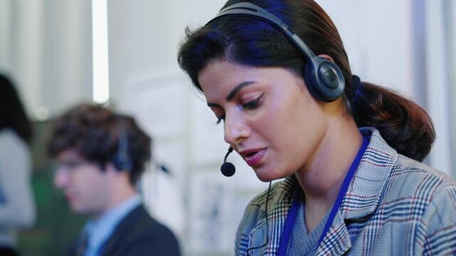 Close-up of a female technology professional wearing a headset with microphone while working in a modern engineering and technology office.
