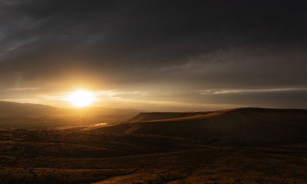 Dramatic sunset scene over hilly terrain with clouds