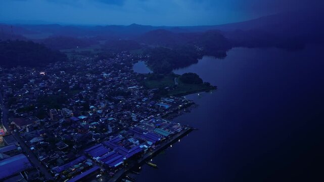 Aerial view over Buhi town and Lake Buhi at dusk in Camarines Sur, Philippines, with Mount Asog, also known as Mount Iriga, in the background. Santa Cruz barangay is visible in the distant landscape.