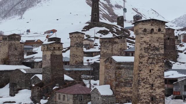 Aerial footage circling an iconic Svan tower as the snow-covered village of Ushguli unfolds below, surrounded by the majestic Caucasus Mountains in Svaneti, Georgia