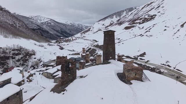 Aerial drone footage soaring above Ushguli, showcasing the village blanketed in snow, traditional stone houses, Svan towers, and the breathtaking winter scenery of the Caucasus.