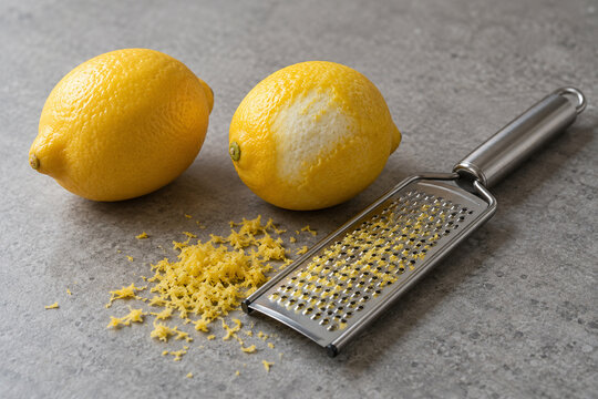 Lemon zest and a stainless steel grater on a kitchen counter