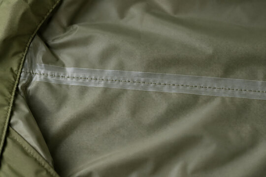 Sealing tape covering stitching on olive technical fabric