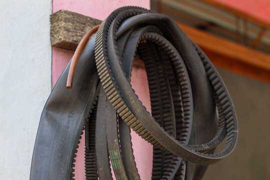 A pile of used motorcycle V-belts and inner tubes hanging on the workshop wall.