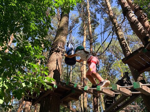 Active family leisure. A little girl navigates an obstacle course at a rope park. Climbing