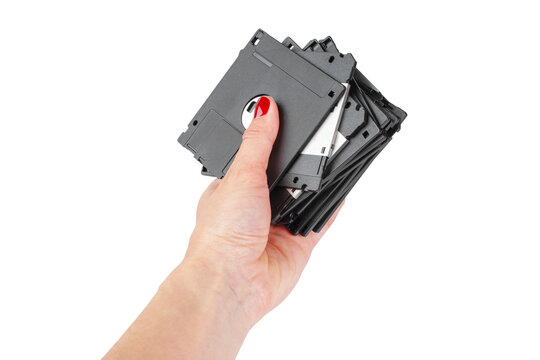 Hand holding a stack of black floppy disks showing the transition from old to new technology in digital storage