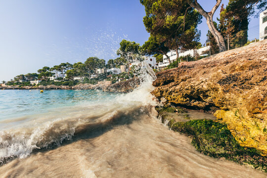Cala Petita waves hitting beach rocks in Mallorca, Spain.