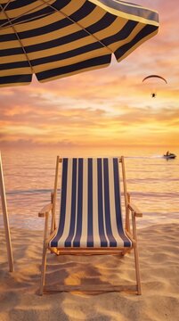 Beach chair and striped umbrella on sandy beach facing sunset sea view