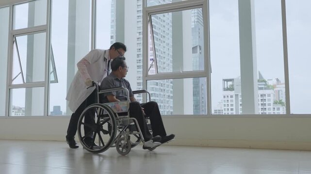 Asian caregiver assisting adult man wheelchair through hospital corridor beside window, city building skyline, urban apartment interior, supportive mobility care, independence, rehabilitation