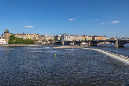 The Prague skyline stands over the Vltava river on a sunny day