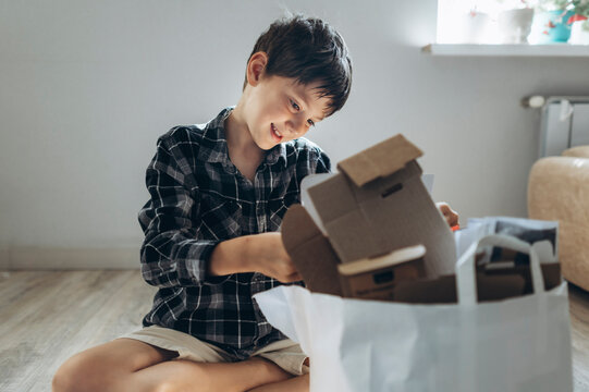 Smiling boy sits on the floor sorting cardboard into a paper bag