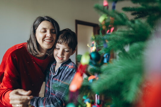 Mother and son decorate a Christmas tree indoors