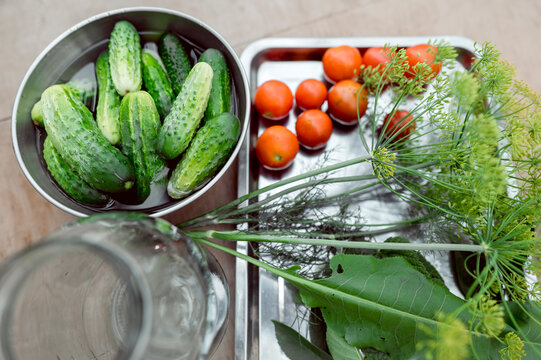 Fresh cucumbers and tomatoes await fermentation in a glass jar