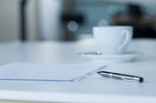Coffee cup, contract and ballpen on desk