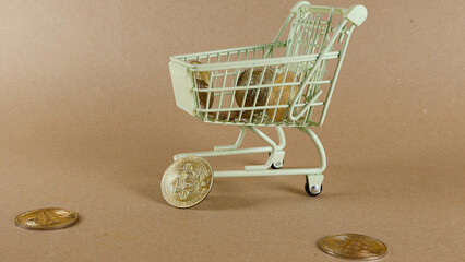Miniature shopping cart filled with golden bitcoin coins and scattered coins on a brown background, symbolizing cryptocurrency transactions, digital commerce, online buying and selling © Dark Artistic