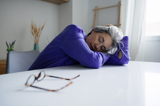 Exhausted woman resting on desk after stressful workday indoors