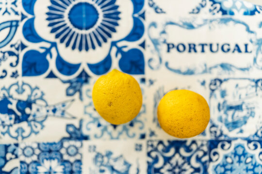 Two fresh lemons lie on a blue Portuguese azulejo patterned cloth