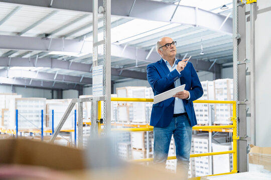 Businessman checks logistics planning with tablet in warehouse