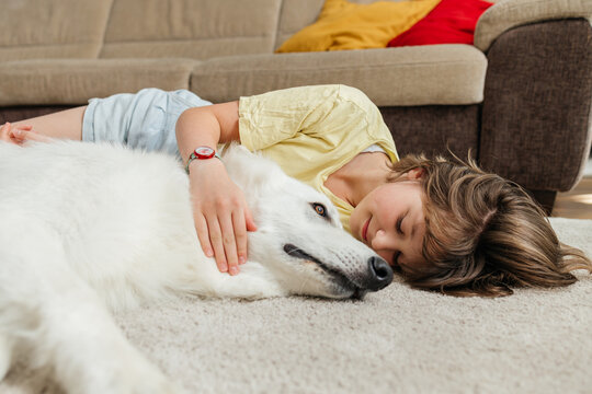 Teenage girl hugs her White Swiss Shepherd on the floor