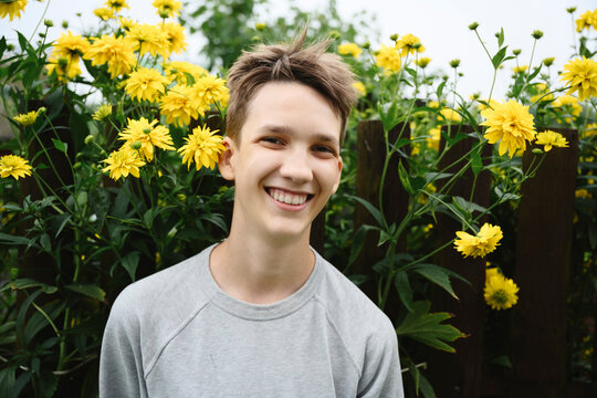 A smiling boy enjoys a summer day outdoors in a flower garden