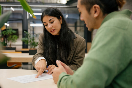 Businesswoman explaining job contract to man in modern office