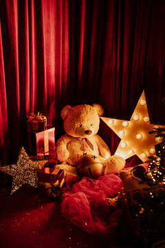 A teddy bear sits with a Christmas gift and a glowing star