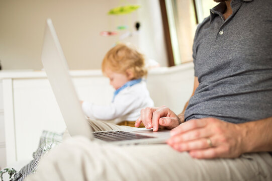 Father at home with his little son using laptop
