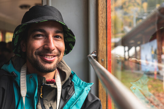 Smiling man wearing hat on vacation in train