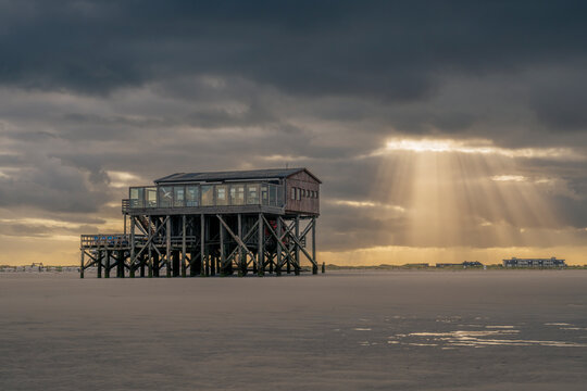 A pile dwelling stands on the beach at sunrise in St Peter Ording