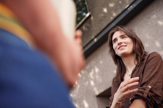 A smiling woman enjoys a fun conversation with a man outside
