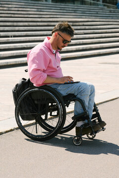 A man in a wheelchair uses a smartphone for navigation in the city