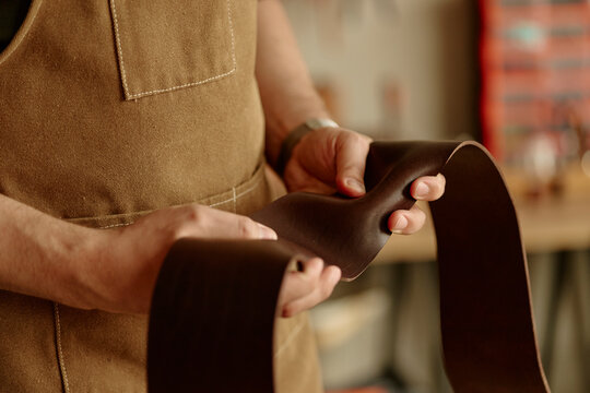 Male artisan prepares leather strap in the workshop