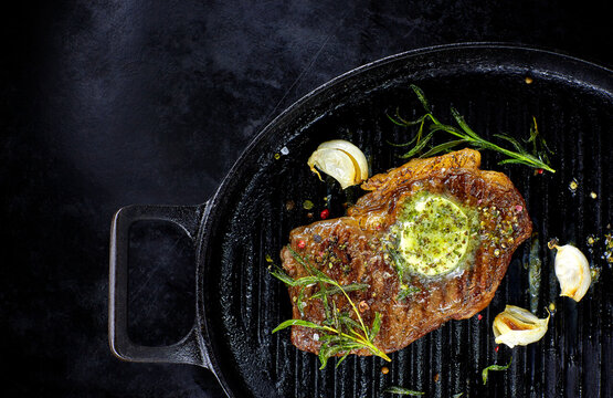 Rump steak with herbed butter, rosmary and garlic in frying pan