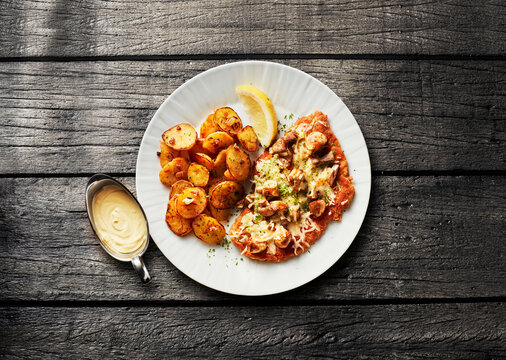 A plate features mushroom schnitzel with fried potatoes and sauce